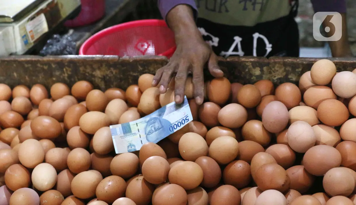 Pedagang telur ayam mengambil uang saat melayani pembeli di Pasar Kelapa Dua, Kabupaten Tangerang, Banten, Rabu (29/12/2021). Kementerian Perdagangan mencatat meroketnya harga telur ayam di sejumlah wilayah jelang pergantian tahun. (Liputan6.com/Angga Yuniar)