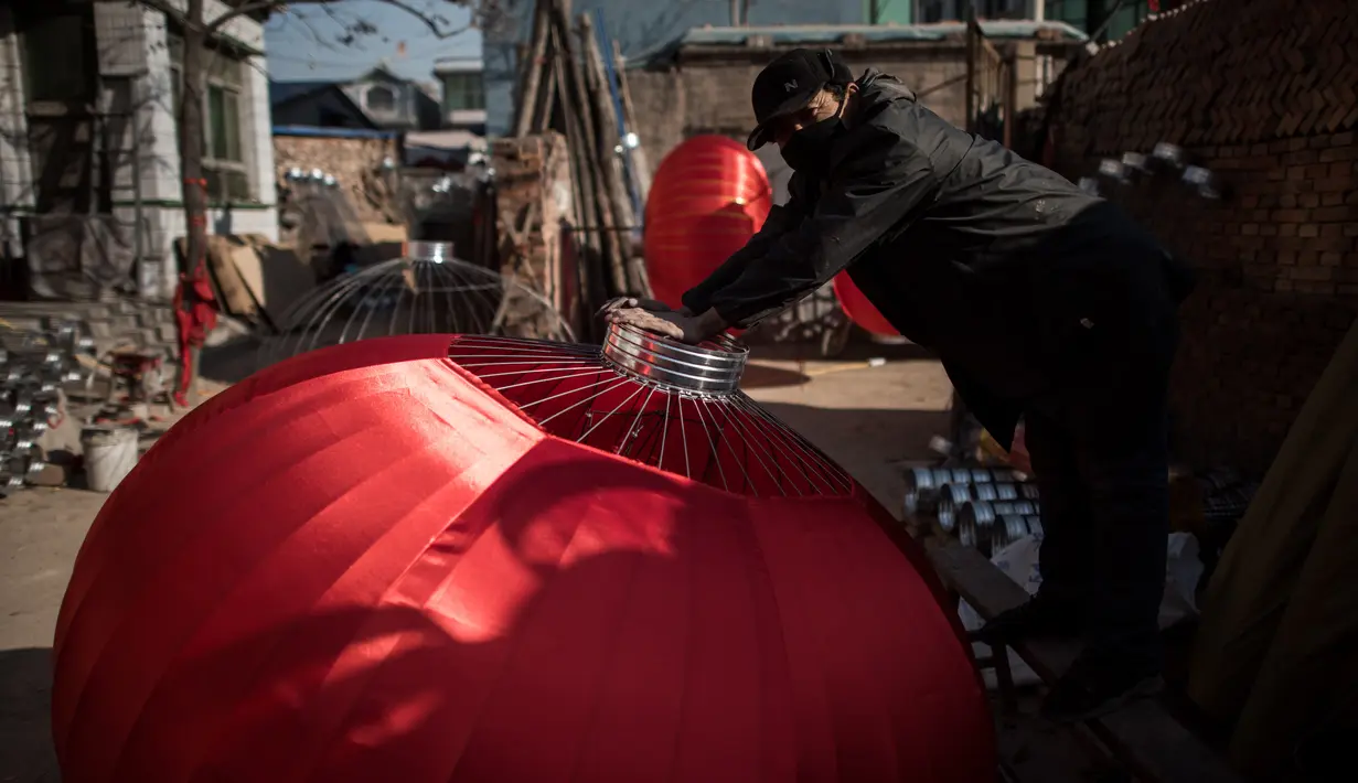 Seorang pekerja sedang merakit lampion merah yang akan dijual untuk menyambut perayaan Tahun Baru Imlek di provinsi Hebei, Tingkok (11/1). (AFP Photo/Fred Dufour)