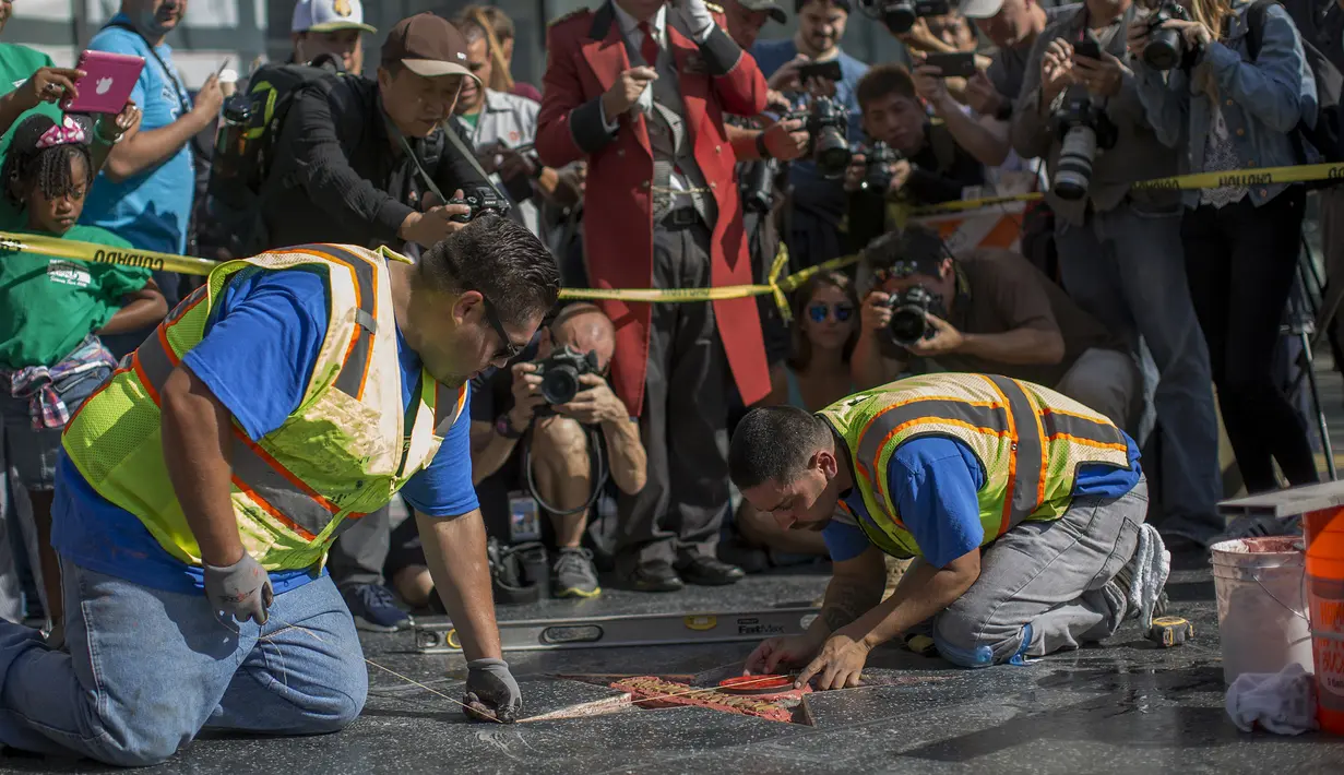 Pekerja memperbaiki Hollywood Walk of Fame milik Donald Trump usai dirusak, California, AS (26/10). Dalam perusakan tersebut James Otis mengenakan pakaian pekerja konstruksi kota dengan membawa sebuah palu dan kapak. (David McNew/Getty Images/AFP)