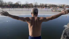 Seorang pria bersiap untuk melompat ke dalam danau Hou Hai yang beku di Beijing, China (24/1). (AFP Photo/Nicolas Asfouri)