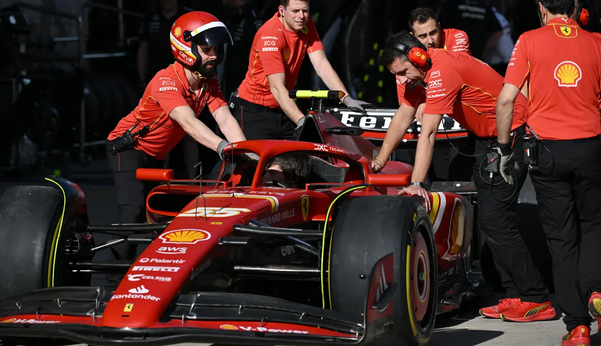 Para mekanik mendorong mobil pembalap Ferrari asal Spanyol, Carlos Sainz, saat mereka berlatih pit stop di Shanghai pada 18 April 2024. (GREG BAKER/AFP)