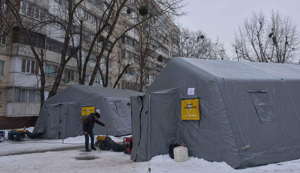 Serangan itu dilaporkan menggempur jaringan listrik di sejumlah wilayah, termasuk kawasan ibu kota Kiev, saat Ukraina dilanda musim dingin. Tampak dalam foto, seorang pria menghangatkan diri di tenda-tenda darurat tempat orang-orang dapat menghangatkan diri setelah serangan udara rutin Rusia terhadap fasilitas energi negara itu di tengah musim dingin, Kyiv, Ukraina, Selasa 13 Januari 2026. (AP Photo/Efrem Lukatsky)