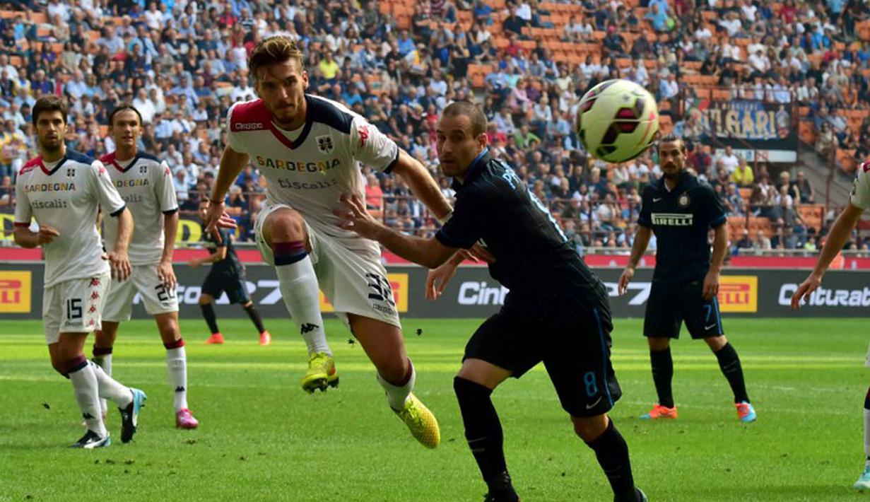 Pemain belakang Cagliari, Luca Ceppitelli (kiri), berusaha membuang bola dari penyerang Inter Milan, Rodrigo Palacio, saat berlaga di Stadion San Siro, Milan, (28/9/2014). Inter Milan kalah 1-4 dari Cagliari. (AFP PHOTO/Giuseppe Cacace)