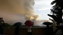 Sejumlah orang menyaksikan Gunung Api Taal erupsi di Tagaytay, Provinsi Cavite, Filipina, Minggu (12/1/2020). Gunung Api Taal mengeluarkan awan abu mencapai 50.000 kaki (15.000 meter) ke atmosfer. (AP Photo/Aaron Favila)
