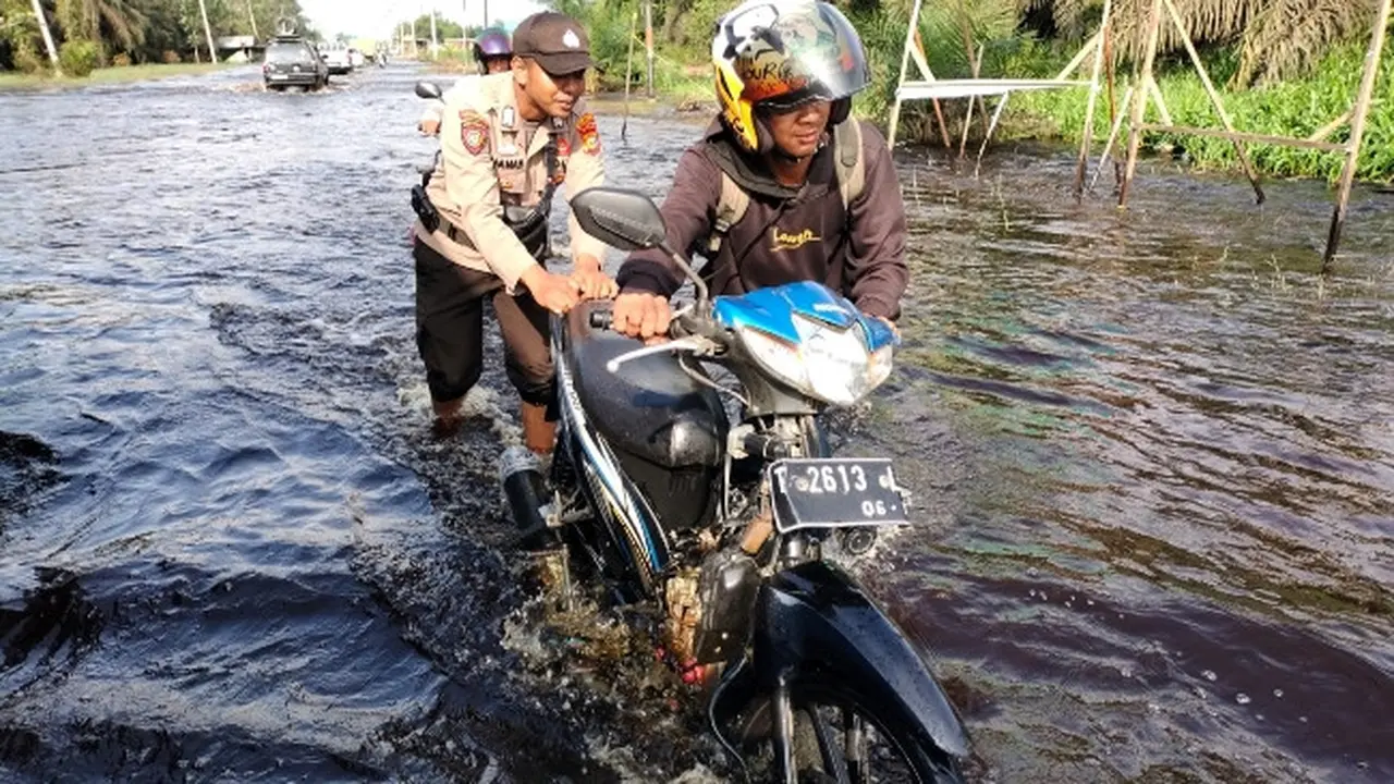 Personel Polres Pelalawan mendorong kendaraan mogok karena nekat melewati banjir di Jalan Lintas Timur Sumatra.