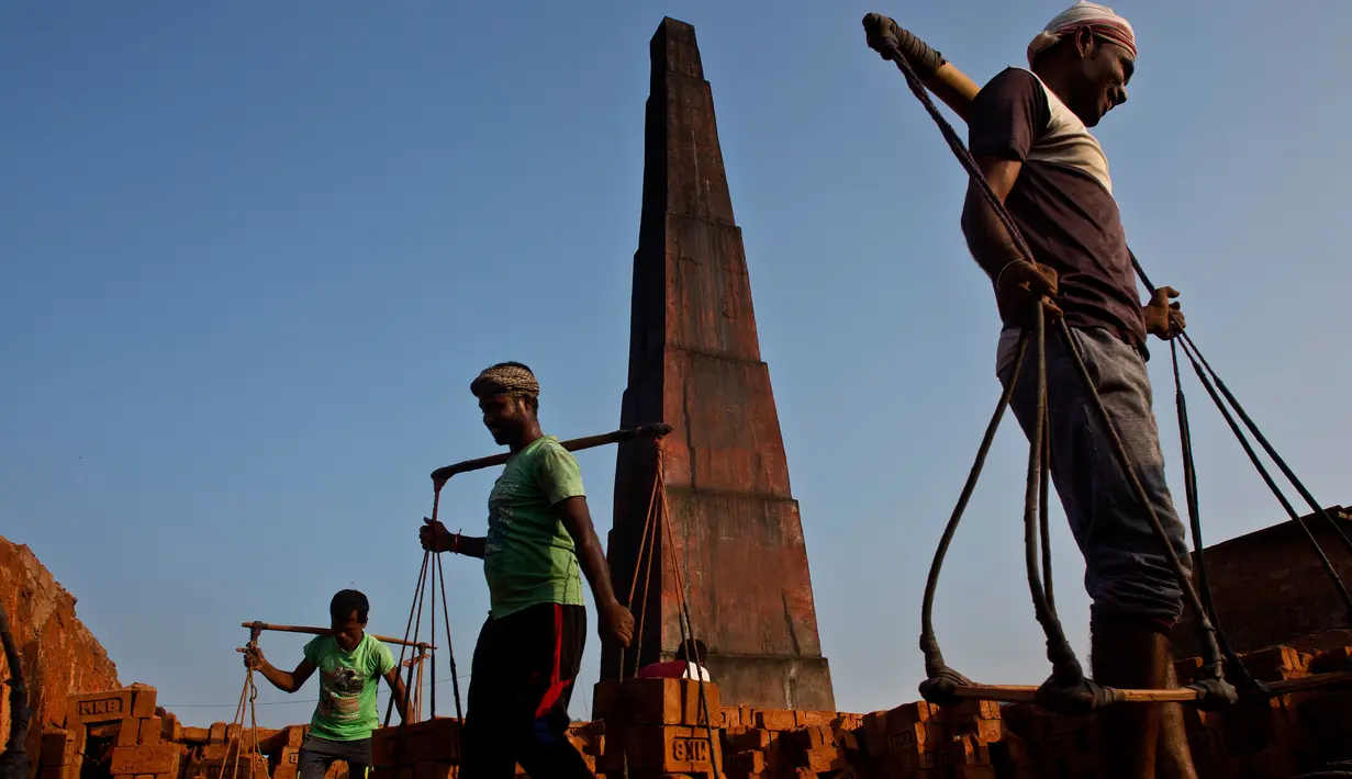 Para pekerja India membawa batu bata di pundak mereka di pabrik pembuatan batu bata di pinggiran Gauhati, India (22/11). Mereka menghasilkan 120 Rupee (kurang dari 2 Dolar) per hari. (AP Photo/Anupam Nath)