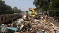 Alat berat merobohkan bangunan di kawasam Rawajati, Jakarta, Kamis (1/9). Penertiban puluhan bangunan liar di kawasan tersebut menyebabkan warga terpaksa menyelamatkan barang berharga mereka ke tepi rel kereta api. (Liputan6.com/Immanuel Antonius)