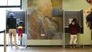 Seorang pria bersama anaknya (kiri) memberikan suara di bilik suara dalam pemilihan umum di Museum Van Gogh, Amsterdam, Belanda, Rabu (17/3/2021). Pemilu digelar selama tiga hari untuk memungkinkan warga memilih dengan aman selama pandemi virus corona COVID-19. (AP Photo/Peter Dejong)