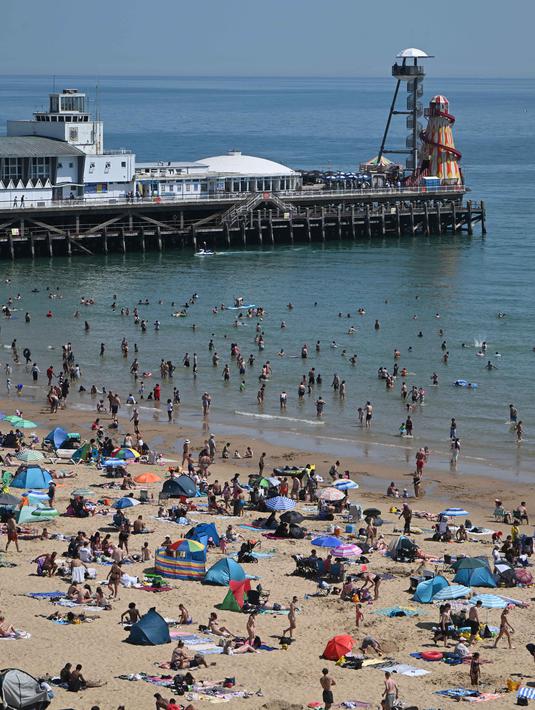 Para pengunjung bermain dan bersantai di bawah sinar matahari di Pantai Bournemouth, Selatan Inggris pada Selasa 26 Mei 2026, saat kondisi gelombang panas menyebar ke sebagian wilayah tenggara Inggris dan London. (JUSTIN TALLIS/AFP)