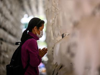 Seorang wanita berdoa di depan lentera teratai putih dengan nama dan doa tertulis pada atasnya setelah kebaktian untuk merayakan ulang tahun Buddha di Kuil Jogye, Seoul, Korea Selatan, Minggu (8/5/2022). (ANTHONY WALLACE/AFP)