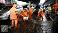 Pekerja Harian Lepas (PHL) membersihkan genangan air di kawasan Rawamangun, Jakarta, Jumat (26/2/2015). (Liputan6.com/Faizal Fanani)