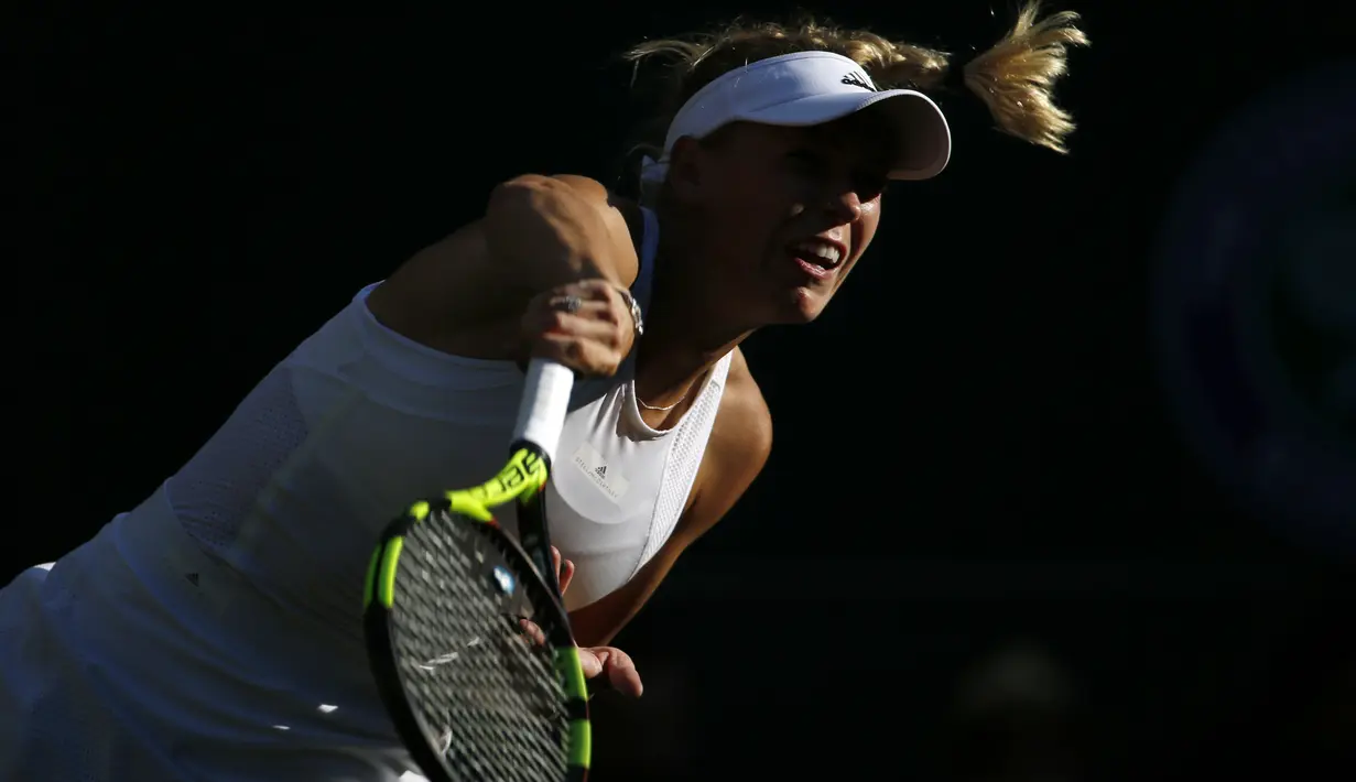 Ekspresi petenis Denmark, Caroline Wozniacki saat mengembalikan bola ke arah lawannya petenis Hungaria, Timea Babos pada laga tunggal putri Wimbledon 2017 di Wimbledon Tennis Championships, London, (4/7/2017). (AP/Alastair Grant)