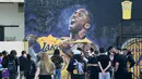 Sejumlah warga berkumpul untuk mengenang wafatnya Kobe Bryant di Staples Center, Los Angeles, Minggu (26/1). Akibat kecelakaan helikopter, legenda NBA itu wafat bersama sang putri. (AFP/Apu Gomes)