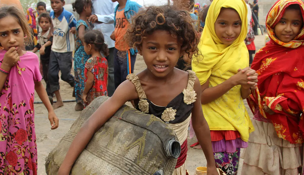 Seorang anak wanita membawa jerigen untuk mengisi air untuk mengisi air bersih di desa Hodeidah, Yaman (17/4). (AFP PHOTO / Stringer)