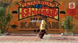 Anak-anak berjalan di depan mural bertema pandemi virus corona COVID-19 di kawasan Sunter, Jakarta, Selasa (2/6/2020). Mural tersebut dibuat sebagai wujud dukungan terhadap tenaga medis serta masyarakat agar tetap semangat menghadapi pandemi COVID-19. (Liputan6.com/Immanuel Antonius)