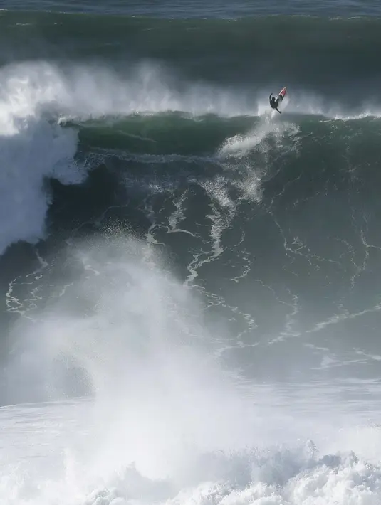 Seorang peselancar keluar dari gelombang selama sesi selancar derek di Praia do Norte atau Pantai Utara di Nazare, Portugal (29/10/2020). Gelombang besar, yang ditimbulkan oleh Badai Epsilon di Atlantik Utara, mencapai Portugis pantai barat menarik peselancar ombak besar ke Nazare. (AP Photo/Pedro R