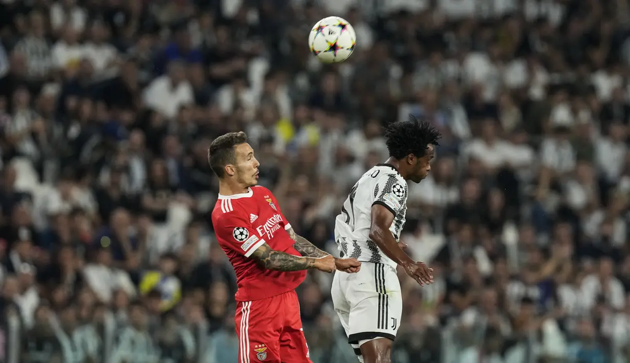 Bek Benfica Alex Grimaldo dan gelandang Juventus Juan Cuadrado melompat untuk berebut bola dalam duel matchday 2 Grup H Liga Champions 2022/2023 di Allianz Stadium, Kamis (15/9/2022) dini hari WIB. Juventus dipermalukan tamunya Benfica dengan skor 1-2. (AP Photo/Antonio Calanni)