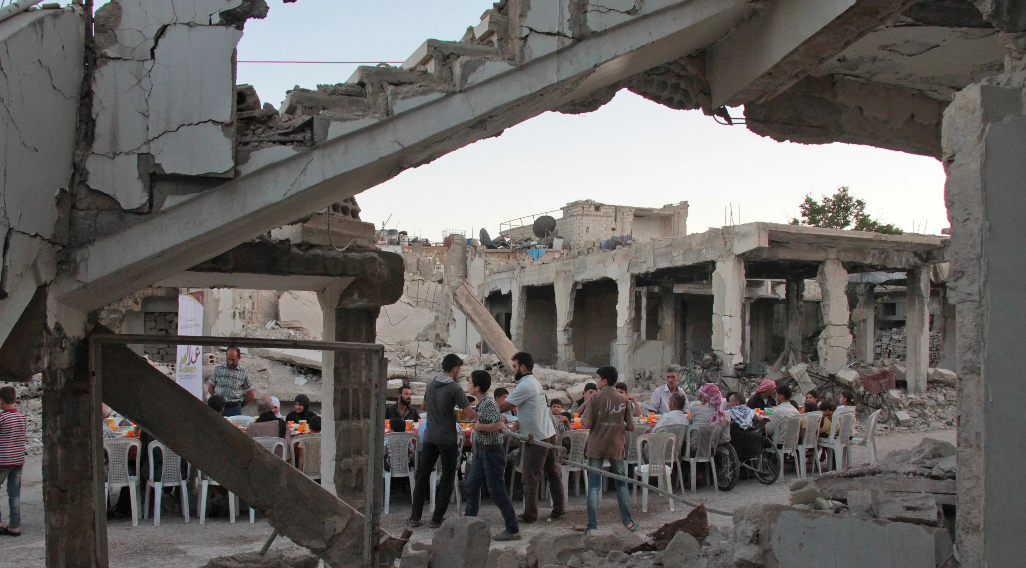 Suasana buka bersama Warga Suriah di tengah reruntuhan bangunan saat bulan suci Ramadan di Kota Douma yang dikuasai pemberontak di pinggiran ibukota Damaskus, Suriah, (18/6). (AFP Photo/Hamza Al-Ajweh)