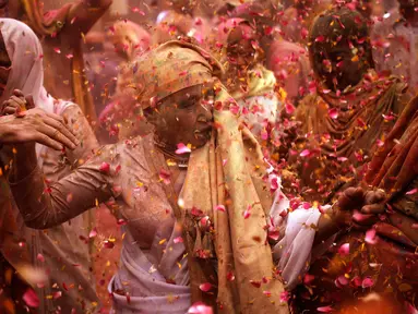 Para janda menari dan saling melempar serbuk berwarna dan kembang saat mengikuti tradisi perayaan Holi di Vrindavan, Uttar Pradesh, India (21/3). Holi merupakan salah satu festival perayaan awal musim semi terbesar di India. (REUTERS/Anindito Mukherjee)