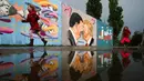 Anak-anak berlari di depan Graffiti yang menggambarkan Presiden AS Trump (kanan) dan Presiden Tiongkok Xi Jinping saling berciuman dengan mengenakan masker di tembok taman umum Mauerpark di Berlin, Jerman, Rabu, (29/4/2020). (AP/Markus Schreiber)