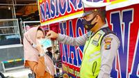 Personel Direktorat Lalu Lintas Polda Riau bagikan masker kepada penggendara saat Operasi Zebra. (Liputan6.com/M Syukur)