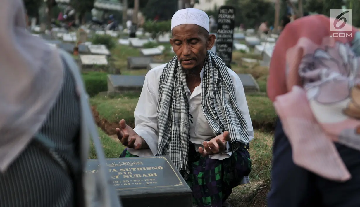 Seorang pria bernama Muhammad Hoir memimpin doa 'Talkin' untuk peziarah di Tempat Pemakaman Umum (TPU) Kemiri, Rawamangun, Jakarta, Selasa (15/5). (Merdeka.com/Iqbal S Nugroho)