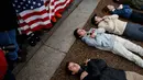 Pengunjuk rasa yang didominasi para siswa SMA berbaring di jalan depan Gedung Putih, Washington, Senin (19/2). Mereka berbaring dengan tangan bersilang di jalan basah di luar Gedung Putih. (AP Photo/Evan Vucci)
