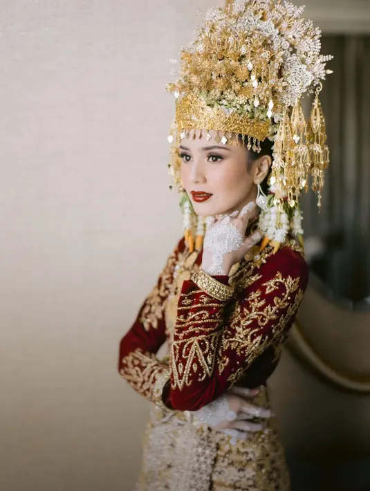 Di momen akad nikah, Beby Tsabina memilih mengenakan baju pengantin adat Aceh berwarna merah. Warna merah bertemu dengan berbagai bordir, payet, dan aksesori emas yang menambah nuansa mewah pada keseluruhan penampilannya. [Foto: Instagram/bebytsabina]