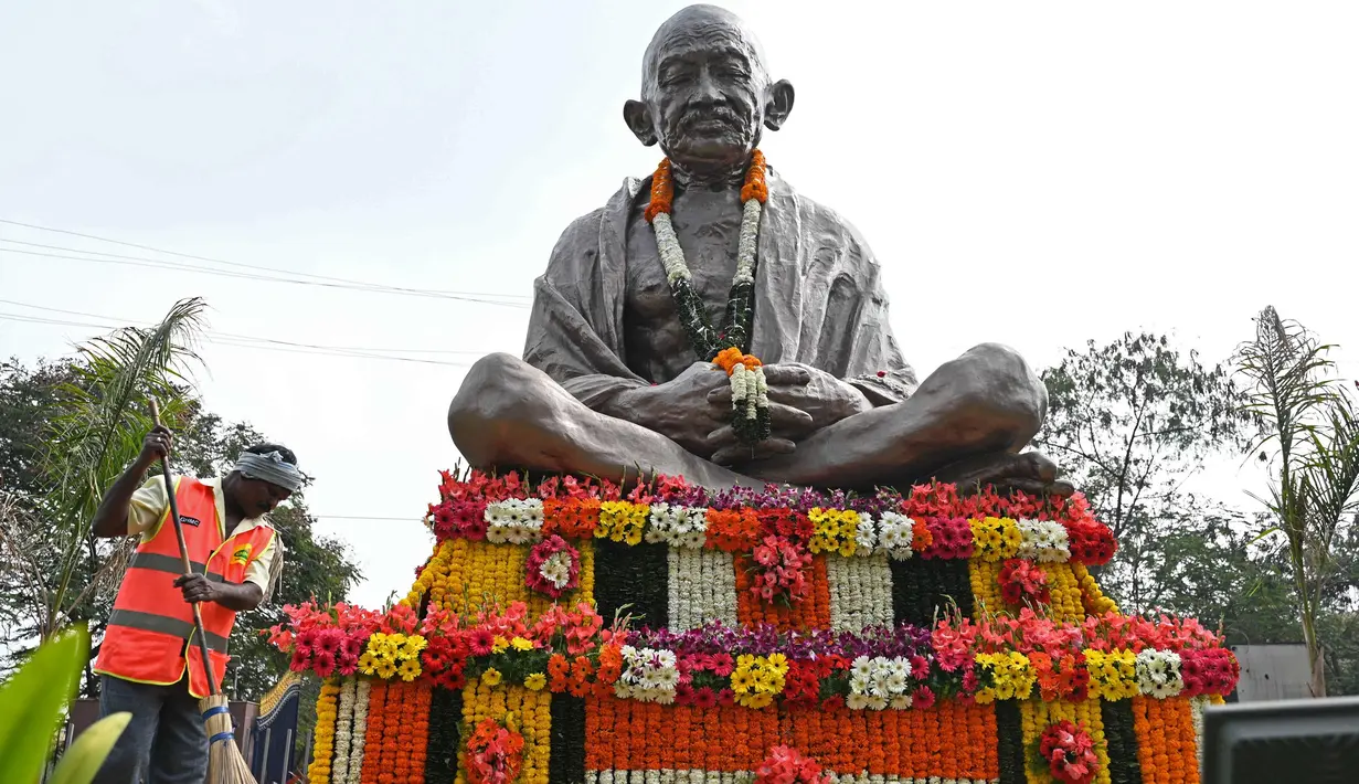 Seorang pekerja kebersihan menyapu di depan patung Mahatma Gandhi pada hari peringatan kematiannya di Hyderabad, India, Senin (30/1/2023). Mahatma Gandhi lahir pada 2 Oktober 1869 dari keluarga pejabat India. Ibunya seorang yang religius dan mengajarkan moral antikekerasan pada Gandhi. (NOAH SEELAM/AFP)