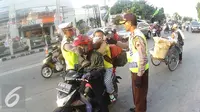 Petugas Kepolisian memberikan masker untuk balita di Simpang Maya, Tegal, Jawa Tengah Minggu (10/7). Pihak Kepolisian menghimbau kepada pengendara motor supaya berhati-hati dalam berkendara. (Liputan6.com/Herman Zakharia)