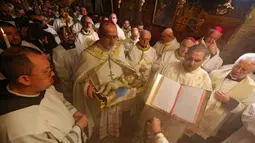 Patriark Latin Yerusalem, Pierbattista Pizzaballa memimpin Misa Malam Natal di Kompleks Gereja Kelahiran Yesus, Bethlehem, Tepi Barat, Minggu (25/12/2022). Setelah dua tahun tutup karena COVID-19, jemaat kembali menghadiri ibadah tersebut kendati jumlahnya tidak sebanyak sebelum pandemi. (Ahmad Gharabli/Pool Photo via AP)