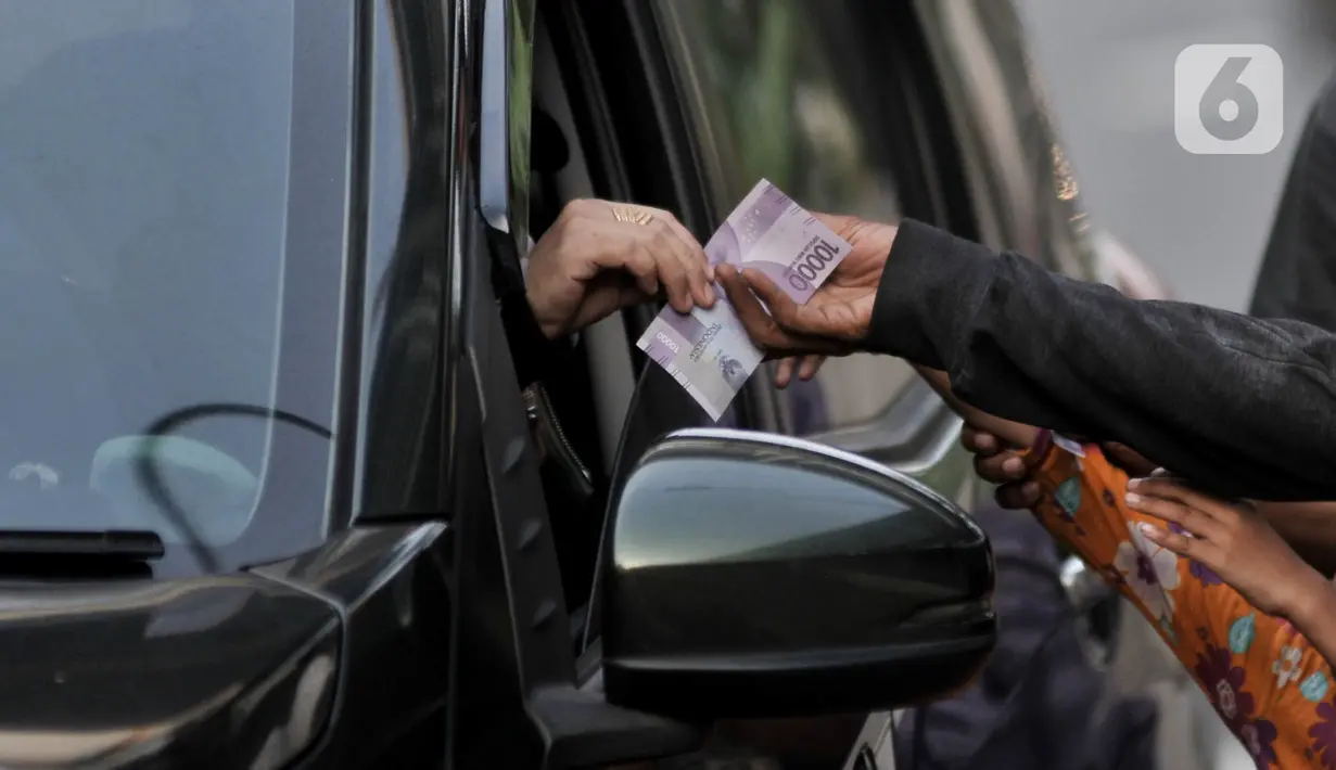 Sejumlah Penyandang Masalah Kesejahteraan Sosial (PMKS) berebut ketika pengendara membagikan uang di pinggir jalan, Jakarta, Rabu (13/5/2020).Demi memenuhi kebutuhan sehari-hari terlebih untuk Lebaran, mereka rela kejar-kejaran dengan petugas saat dirazia. (merdeka.com/Iqbal S. Nugroho)