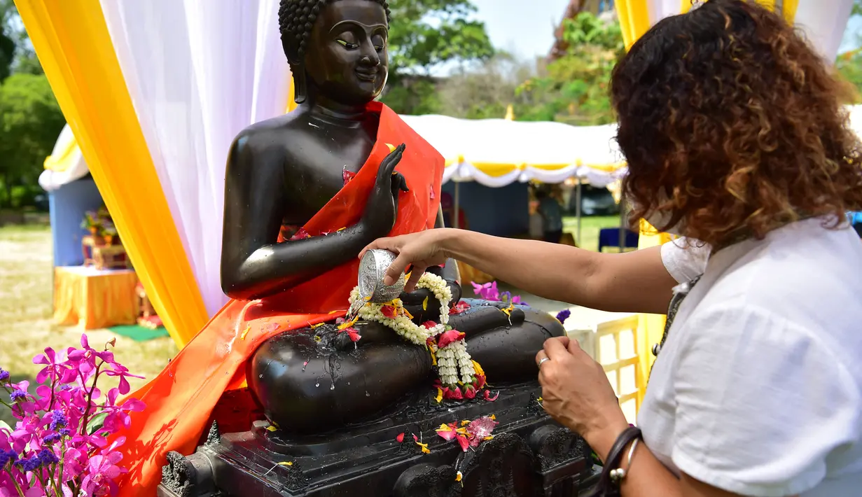 Seorang umat Buddha menuangkan air ke patung Buddha selama perayaan Tahun Baru Buddha, yang secara lokal dikenal sebagai Songkran, di kuil Prachapirom di Narathiwa (12/4/2022). (AFP/Madaree Tohlala)