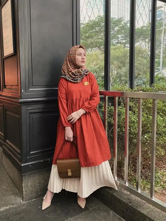 Cocok untuk hangout, padukan tunik model A-Line warna merah dengan rok plisket warna cream. Untuk hijab, kamu bisa memilih hijab dengan aksen bermotif seperti yang dikenakan influencer Dwi Handayani satu ini (Instagram/dwihandaanda).