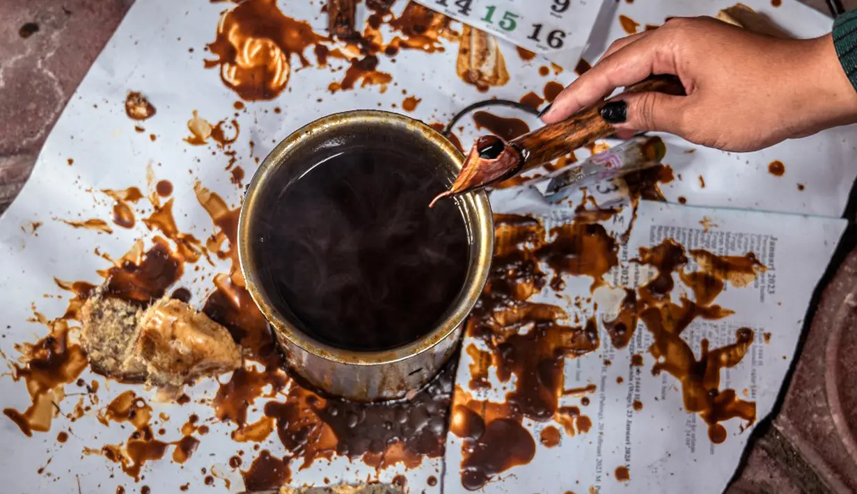 Seorang pekerja menggunakan alat yang disebut 'canting' untuk mengoleskan lilin panas ke kain batik saat proses pembuatan di Sidoarjo, Jawa Timur, Sabtu (1/10/2022). Indonesia akan memperingati Hari Batik Nasional pada 2 Oktober. (JUNI KRISWANTO/AFP)