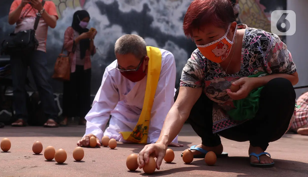 Warga keturunan Tionghoa mencoba mendirikan telur saat perayaan Peh Cun di Khongcu Bio Litang di Pasar Lama, Kota Tangerang, Kamis (25/6/2020). Prosesi yang digelar setiap tanggal 5 bulan 5 penanggalan Tionghoa itu menjadi ungkapan syukur atas segala rezeki dari Tuhan. (Liputan6.com/Angga Yuniar)