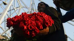 Pedagang merapihkan bunga mawar saat mereka menunggu pelanggan di pasar bunga grosir di Kolkata, India (7/2). Jelang perayaan hari Valentine, bunga mawar banyak diburu dari tanggal 7 Februari dengan ditandai dengan Rose Day. (AFP Photo/Dibyangshu Sarkar)