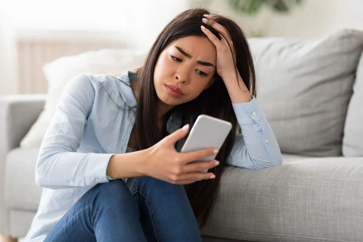 perempuan stres memegang ponsel