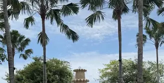 Enzy Storia liburan lebaran bersama suaminya ke Bali. Tampak ia mengenakan outer cardigan abu-abu dipadukan inner tanktop putih serta celana panjang hitam. Membawa tas tote bag besar, serta flat shoes putih. [@enzystoria]
