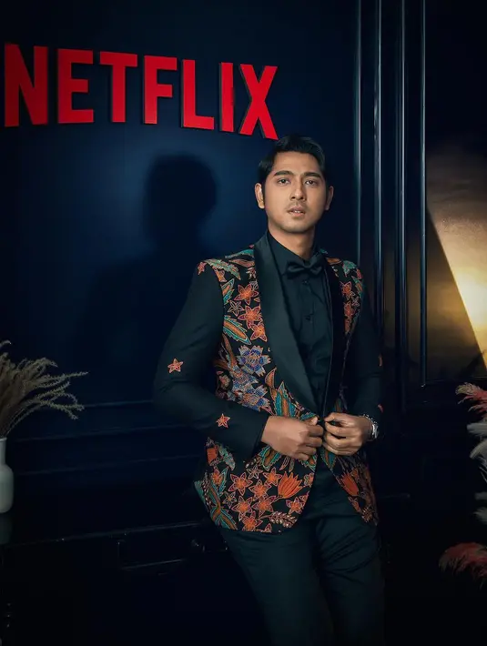 Menarik, Arya Saloka di red carpet Busan Film Festival mengenakan jas batik. Jas hitam bermotif batik floral bernuansa oranye dipadu dengan kemeja, celana panjang, dan dasi kupu-kupu hitam. [Foto: Instagram/netflixid]