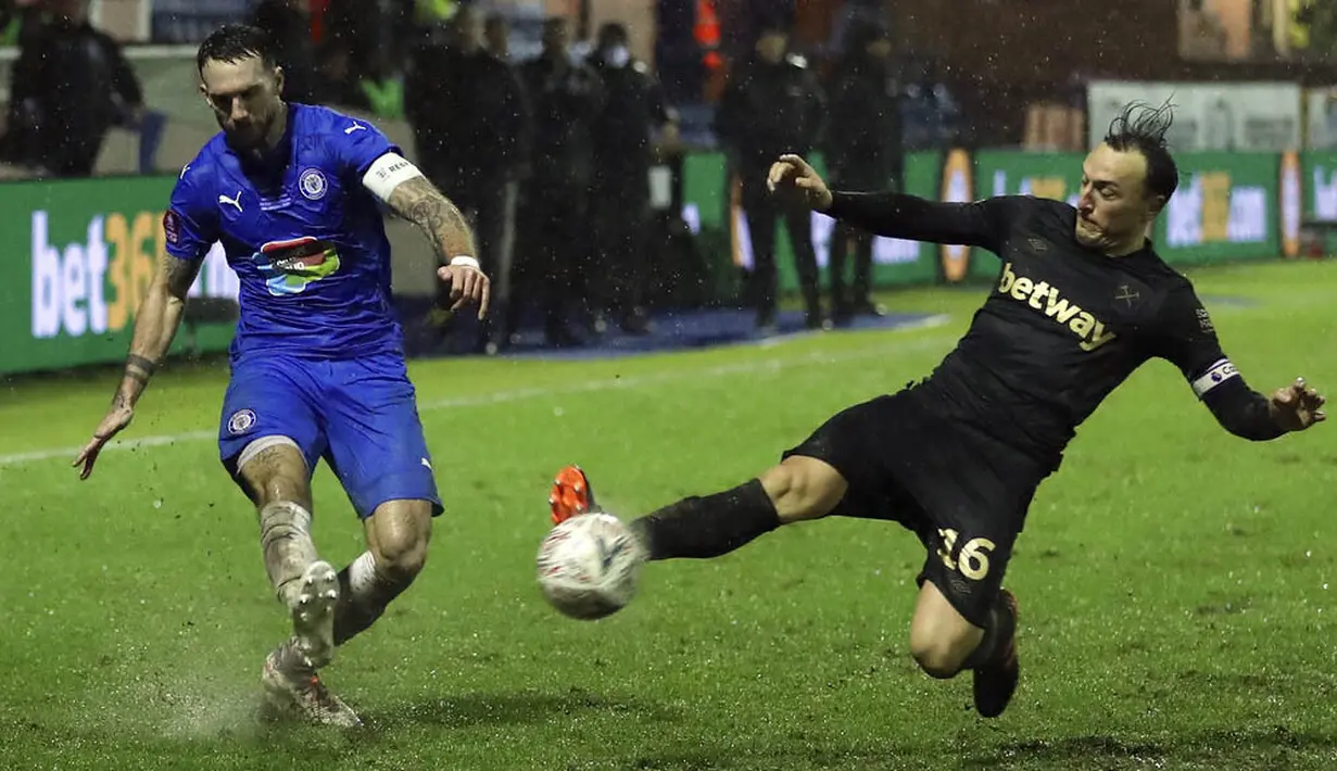 Pemain West Ham United, Mark Noble, berusaha menghalau tendangan pemain Stockport County, Liam Hogan,  pada laga Piala FA di Stadion Edgeley Park, Senin (11/1/2021). West Ham United menang dengan skor tipis 1-0. (Martin Rickett/Pool via AP)