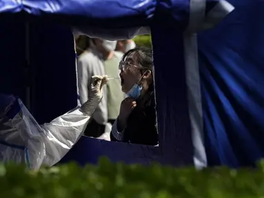 Seorang warga menjalani tes COVID-19 di luar gedung perkantoran di Distrik Haidian, Beijing, China, Selasa (26/4/2022). Beijing memberlakukan pengujian massal dan menutup akses ke lingkungan karena berupaya menahan wabah COVID-19 baru. (AP Photo/Ng Han Guan)