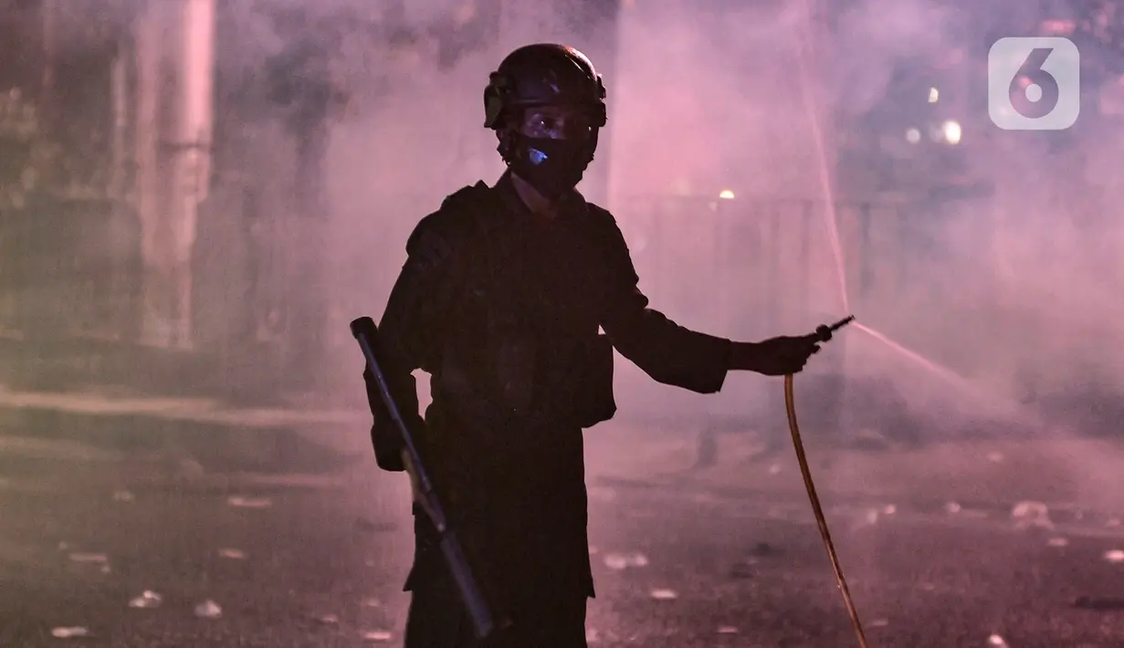 Seorang polisi saat berupaya membubarkan massa di kawasan Harmoni, Jakarta, Kamis (8/10/2020). Polisi berhasil membubarkan unjuk rasa ricuh yang dilakukan massa penolak UU Cipta Kerja dengan tembakan gas air mata dan watercanon. (merdeka.com/Iqbal S. Nugroho)