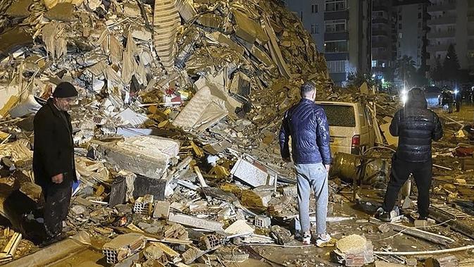 Orang-orang berusaha menjangkau warga yang terperangkap di dalam bangunan yang runtuh di Diyarbakir, Turki selatan, Senin dini hari, 6 Februari 2023. Gempa berkekuatan magnitudo 7,8 telah menyebabkan kerusakan signifikan di tenggara Turki dan Suriah dan dikhawatirkan banyak korban jiwa. (Depo Photos via AP)