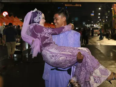 Pasangan Aldona Febrianti dan Septian Maulana meluapkan kebahagiaan usai ijab kabul di jalan MH Thamrin, Jakarta, Senin (31/12). 557 pasangan mengikuti nikah massal dan isbat nikah pada malam pergantian tahun 2018-2019. (Liputan6.com/Helmi Fithriansyah)