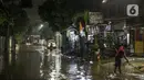Warga membersihkan depan rumah yang tergenang banjir di kawasan Mampang Prapatan, Jakarta, Sabtu (13/11/2021). Intensitas hujan yang tinggi sejak sore di Jakarta membuat kawasan permukiman di Mampang Prapatan tergenang banjir dengan tinggi sebetis orang dewasa. (Liputan6.com/Faizal Fanani)