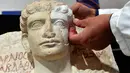 Peneliti memasangkan bagian wajah yang hilang dari sebuah patung yang berumur sekitar 2-3 abad di Roma, Kamis (16/2). Patung tersebut hancur akibat dari serangan ISIS. (AFP PHOTO / Alberto PIZZOLI)
