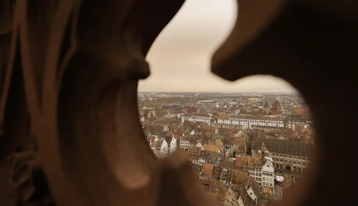 Pemandangan kota Strasbourg tampak diselimuti debu Sahara berwarna oranye bergerak di atas kota di Prancis timur (15/3/2022). Badai di gurun Sahara menciptakan badai besar hembusan angin, yang mengangkat pasir ke udara. (AP Photo/Jean-Francois Badias)