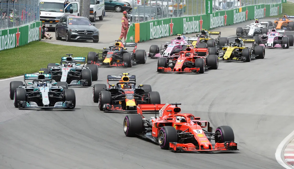 Pembalap Ferrari, Sebastian Vettel memimpin balapan di awal Formula1 Grand Prix (GP) di Montreal, Kanada, Minggu (10/6). Kemenangan Vettel mengambil alih puncak klasemen sementara dari tangan Lewis Hamilton. (Tom Boland/The Canadian Press via AP)