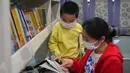Seorang wanita dan anak memilih buku di  perpustakaan keliling di sebuah lingkungan permukiman di Changsha, Provinsi Hunan, China tengah (26/3/2020). Baru-baru ini, perpustakaan keliling di Changsha kembali beroperasi di tengah langkah-langkah pencegahan dan pengendalian epidemi. (Xinhua/Chen Zeguo)